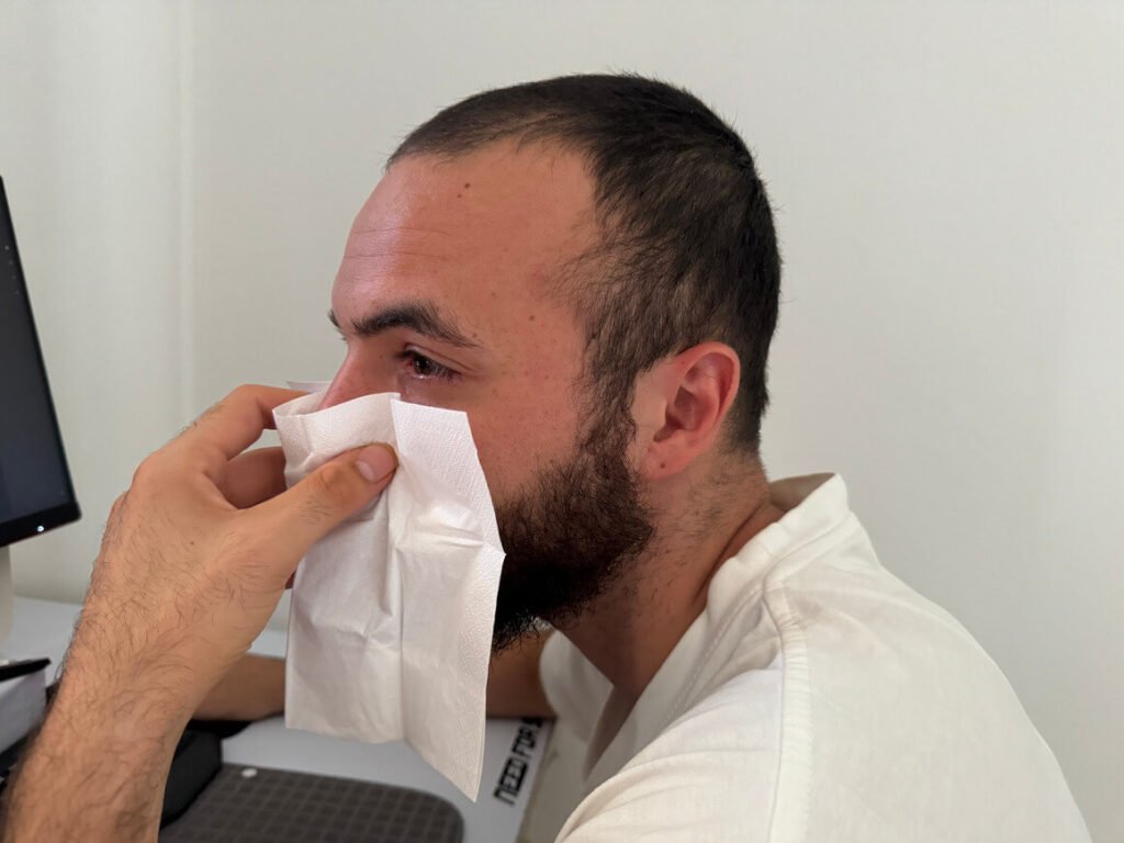 man suffering from sinus infection using a tissue