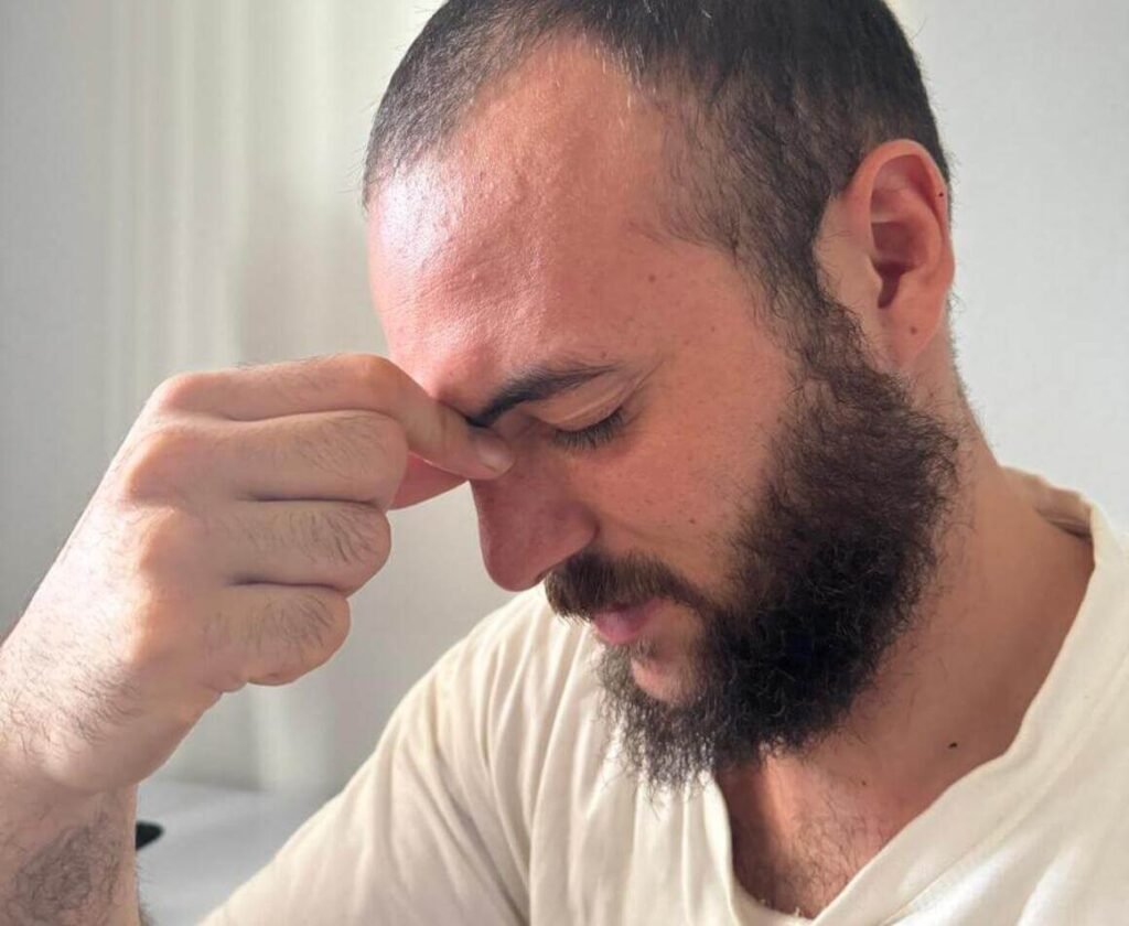 A man pressing the area between his eyes, visibly experiencing dizziness