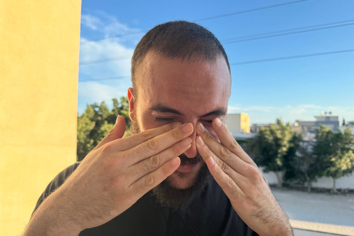 Man grimacing and applying pressure to his sinues with his fingers due to intense sinus pressure