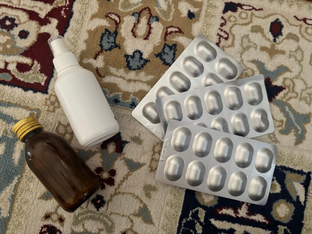 Assorted sinus infection relief items: dark bottle of syrup, nasal spray, and three bars of antibiotics